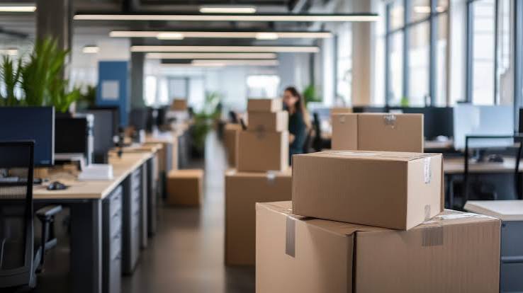 Packed moving boxes stacked in an open-plan office mid-relocation